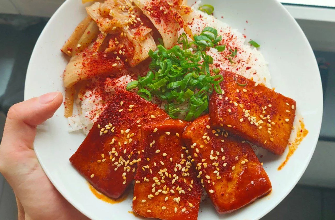 Koreanischer geschmorter Tofu serviert auf Reis mit Kimchi, garniert mit Sesamsamen und Frühlingszwiebeln